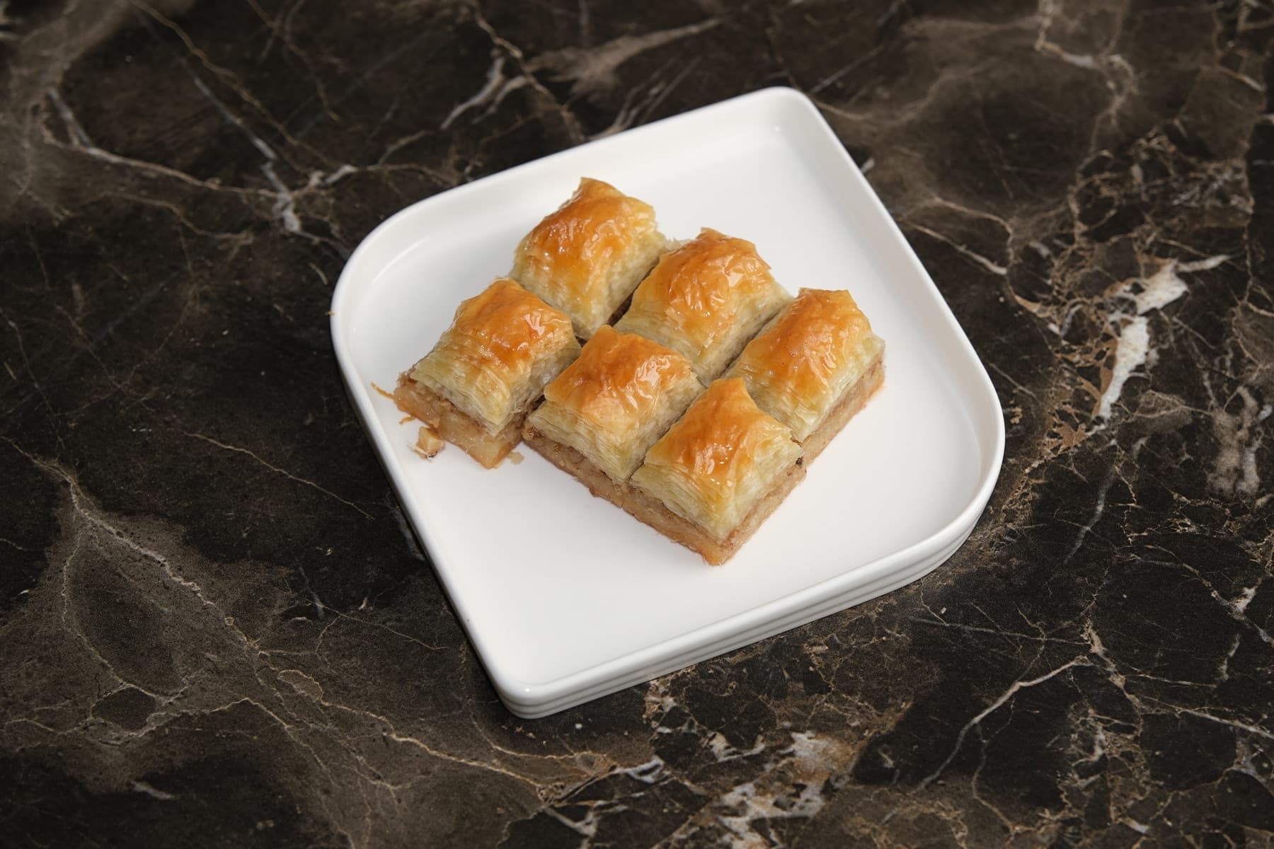 Beyaz tabakta cevizli baklava porsiyonu